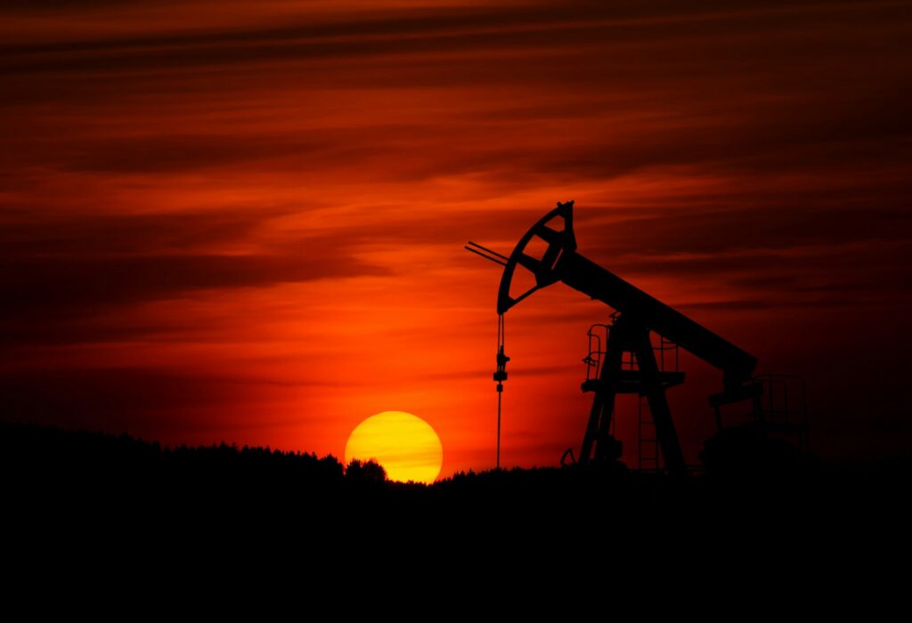 Oil pump jack silhouetted against a red sunset